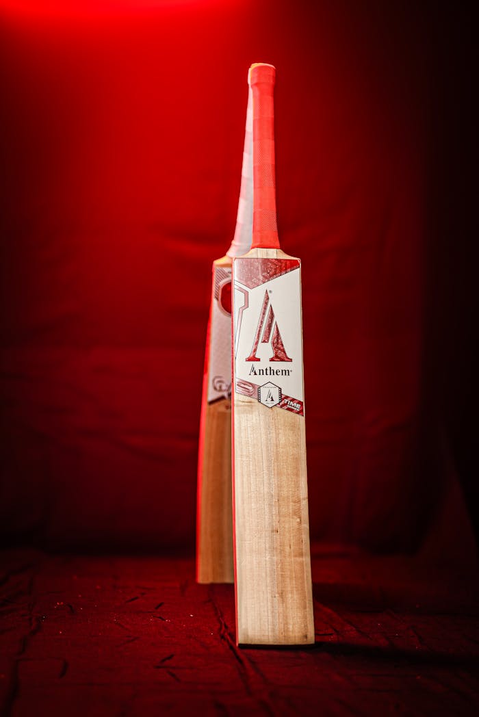 A striking image of a cricket bat illuminated by red light, showcasing sporting equipment.